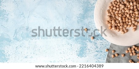 Plate with dry chickpeas on light blue background with space for text