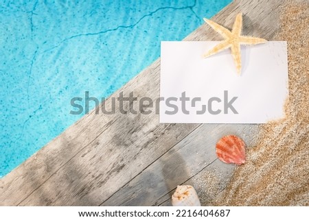 Invitation card without inscription seen from above on a wooden pavement above a pool with a starfish. Atmosphere vacations in summer.	