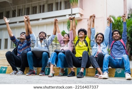 Excited group of students shouting by holding eachother hands after exams at on college campus - concept of friendship, bonding, happiness Royalty-Free Stock Photo #2216407337