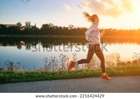 Woman runs in the park on autumn morning. Healthy lifestyle concept, people go in sports outdoors. Silhouette family at sunset. Fresh air. Health care, authenticity, sense of balance and calmness. Royalty-Free Stock Photo #2216424429