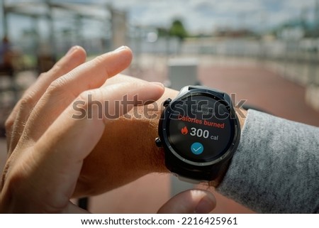 A man at the stadium checks the number of calories burned in his smartwatch. Daily exercise in the fresh air for weight loss. Smart gadgets for sports. wristwatch concept Royalty-Free Stock Photo #2216425961