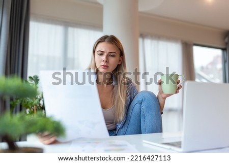 Serious frowning woman sit at workplace desk looks at laptop screen read e-mail feels concerned. Bored unmotivated tired employee, problems difficulties with app