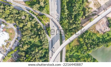Aerial view directly above a six lane highway. Top view of asphalt road passes through the field and forest. Aerial. Sedan cars driving by the highway. Top view from drone. aerial photo autobahn road Royalty-Free Stock Photo #2216440887