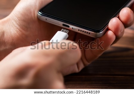 Man hands plugging a charger in a smart phone. Man using smartphone with powerbank. Man charging battery on mobile phone at home