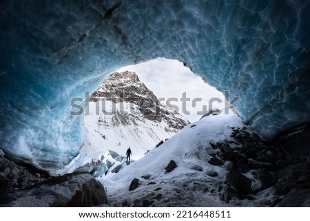 Blue textured ice cave exploration with a silhouette of a hiker in Arolla glacier, Valais Switzerland Royalty-Free Stock Photo #2216448511
