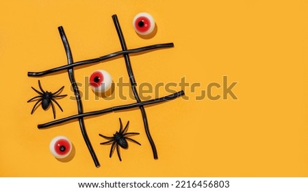 Game tic-tac-toe from spiders and eyes on orange background. Halloween party