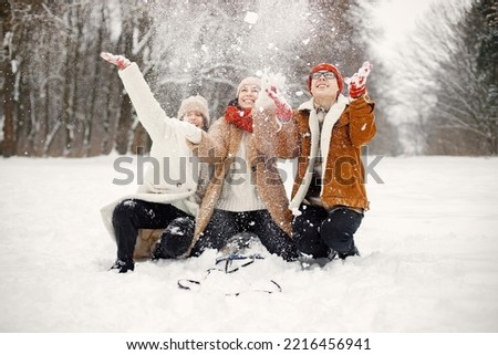 Teen siblings and their mother riding a sled at winter park