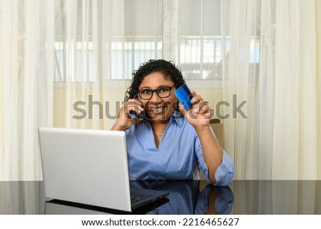 woman talking on her cell phone retains an online shopping payment card