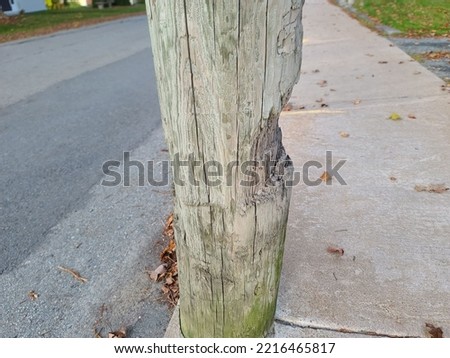 A power pole with a big chunk of wood missing from the side of it.