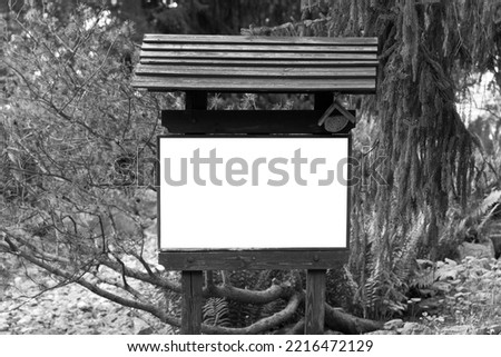 A white sheet of paper on a wooden information carrier with a mockup installed in a forest park. Black and white photo