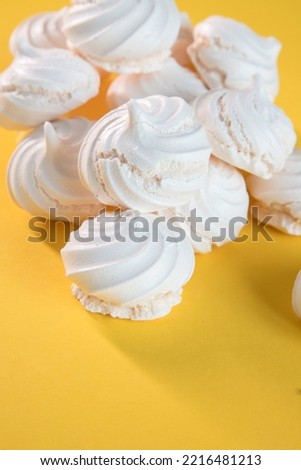 "Suspiros" or meringue, sweet made with egg whites, sugar and a few drops of lemon on a yellow background.
