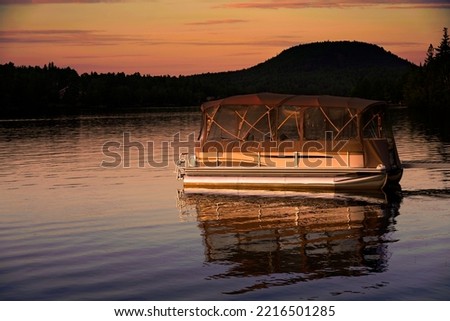 A picture of a pontoon boat on lake with a evening sunset Royalty-Free Stock Photo #2216501285