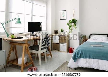 Cozy interior millennial teenage room with bed, laptop and desk Royalty-Free Stock Photo #2216507759