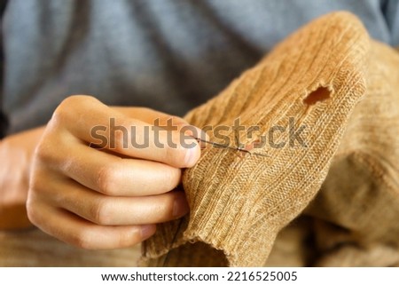 Mending clothes. Old worn woolen clothes. Repair concept, selective focus Royalty-Free Stock Photo #2216525005