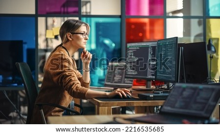 Female Junior Software Engineer Writes Code on Desktop Computer With Two Monitors and Laptop Aside In Stylish Office. Caucasian Woman Working On Artificial Intelligence Service For Big Tech Company.