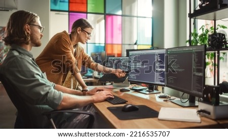 Male Programmer Shows Progress to Female Start-Up CEO on Desktop Computer in Creative Office Space. Caucasian Man and Woman Discussing New Features For Artificial Inteligence Software. Royalty-Free Stock Photo #2216535707