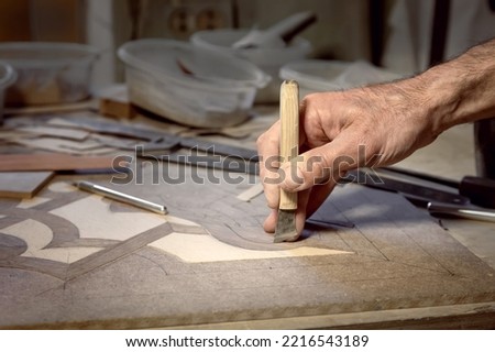 The carpenter's hand makes a mosaic of wood. Wood inlay. Handmade woodwork. Tools for woodworking. Royalty-Free Stock Photo #2216543189