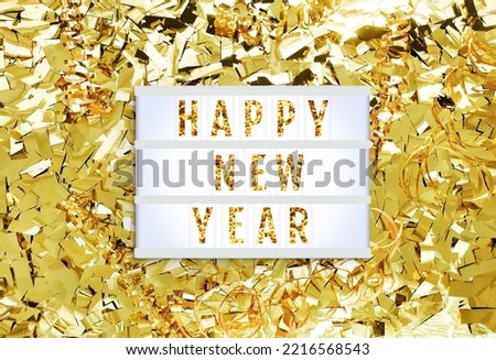 Happy New Year lightbox on a shining golden background of tinsel confetti, ribbons. Text frame of the lightbox with the inscription Happy New Year. Holiday mockup. Top view, close up