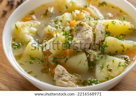 Chicken soup with potatoes and noodles on a wood - close up view