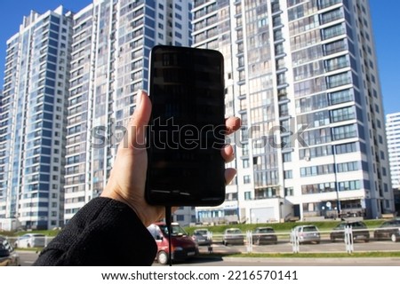 A phone in your hand against the backdrop of tall modern buildings