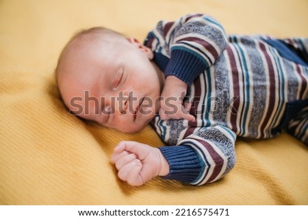 two week old very cute baby in overalls on an orange plaid
