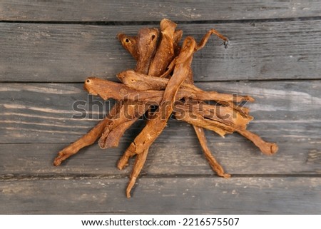 Chewy and delicious chiken jerky, dried meat cut into slices on a wooden background, warm picture