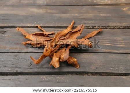 Chewy and delicious chiken jerky, dried meat cut into slices on a wooden background, warm picture