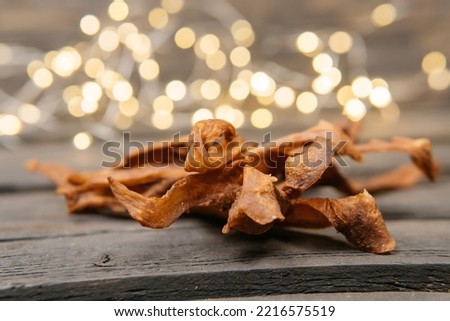 Chewy and delicious chiken jerky, dried meat cut into slices on a wooden background, warm picture with bokeh
