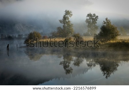 Fog  and mist layers lightly covers the calm mirror like St. Joe River near St. Maries, Idaho. Royalty-Free Stock Photo #2216576899