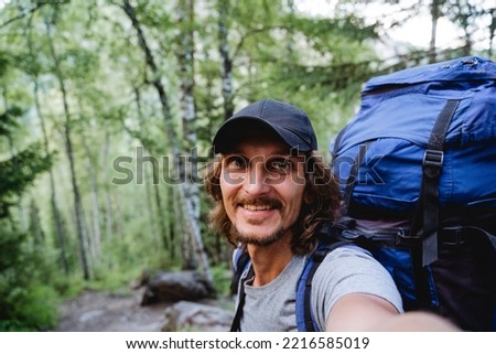A guy's smile, a selfie on the phone, a blogger shoots realms, video content for social networks, a hipster in a cap, a man on a hike with a backpack portrait of himself. High quality photo