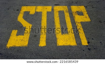 yellow block print of 'STOP' on road
