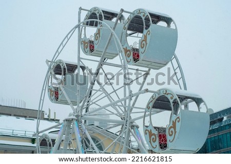 Russian attraction "Ferris wheel" on the street in winter. Cabins of an attraction, a rotating wheel. Ferris wheel in Russia. Winter entertainment for the New Year holidays. big wheel in winter