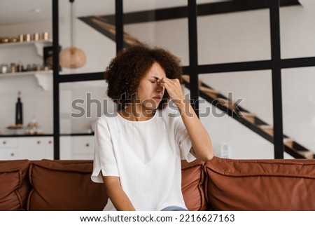 Sick African girl with sinusitis is holding her stuffy nose because she has rhinitis and is planning to go to the ENT doctor Royalty-Free Stock Photo #2216627163