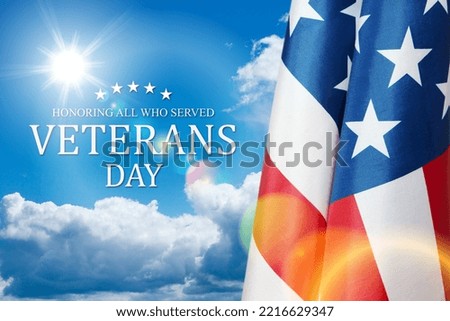 American flags with Text Veterans Day Honoring All Who Served on blue sky background.