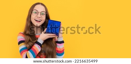 happy teen girl in eyeglasses holding present box for holiday, surprise. Kid girl with gift, horizontal poster. Banner header with copy space.