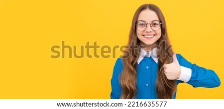 Happy nerdy-looking girl child give thumbs up satisfaction hand gesture yellow background, childhood. Child face, horizontal poster, teenager girl isolated portrait, banner with copy space.