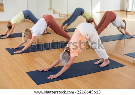 Group of sporty women of different ages exercising during yoga class in modern studio