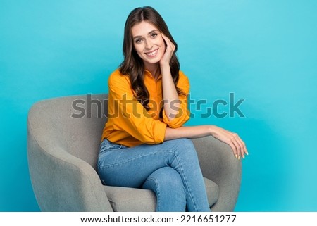 Photo of pretty positive person sit chair arm touch cheekbone toothy smile isolated on blue color background