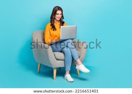 Full size photo of pretty positive girl sit use netbook write typing email isolated on blue color background