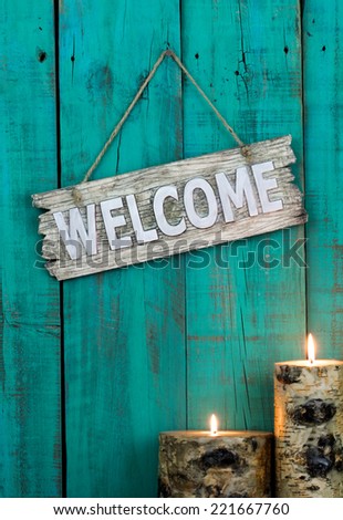 Wood welcome sign by candlelight hanging on antique teal blue rustic wooden door