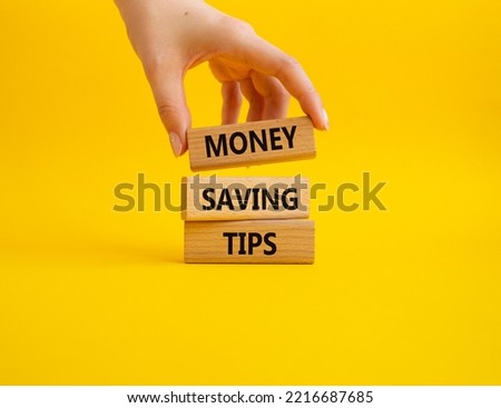 Money saving tips symbol. Concept words Money saving tips on wooden blocks. Beautiful yellow background. Businessman hand. Business and Money saving tips concept. Copy space.