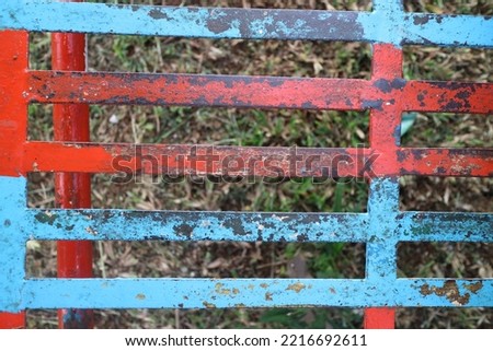 a photo of a iron trellis with red and blue paint that has peeled off