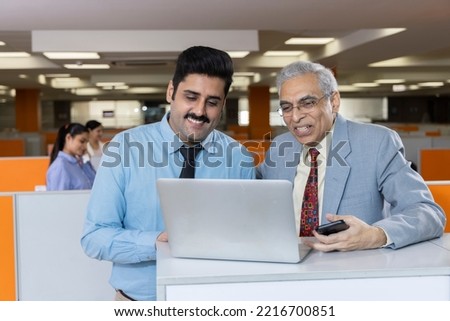 Happy mature businessman and his young assistant working in office.