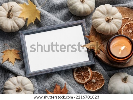 Autumn composition. Photo frame, pumpkins, dried leaves on grey knitted background. Autumn, fall, halloween, thanksgiving concept. Flat lay, top view, copy space