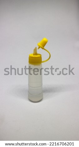 Glue bottle with yellow cap isolated on a white background.