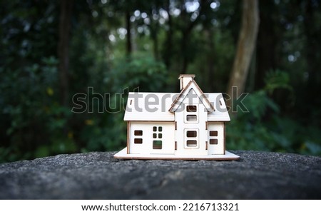 Small wooden toy house model placed on forest.  Nature and real estate concept.