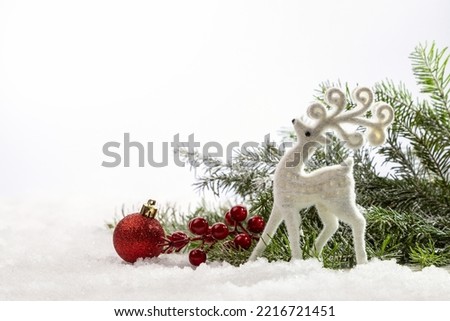 Red Christmas decorations under a fir tree on white snow. Copy space.