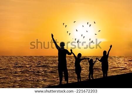 Silhouette of happy family on beach watching sunset together