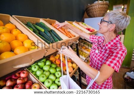 Mature woman buying goods in fruits and vegetables shop. Royalty-Free Stock Photo #2216730165