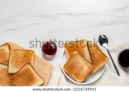 Slices of tasty toasted bread and jam on white marble table, flat lay. Space for text